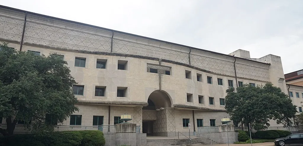 A street view of a limestone building with an arch and text engraved in stone that reads "Louise and James Robert Moffett Molecular Biology Building"